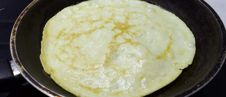 A pancake cooking in a pan.